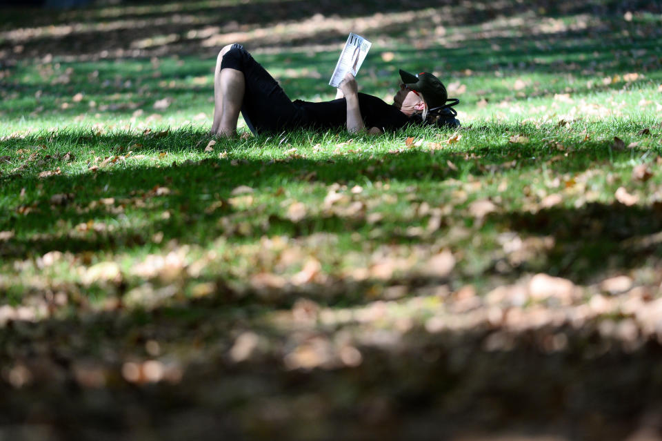 A women reads a magazine in the sunshine in Green Park, London, in autumn, as the Met Office said 2018 was the second sunniest on record. (PA).