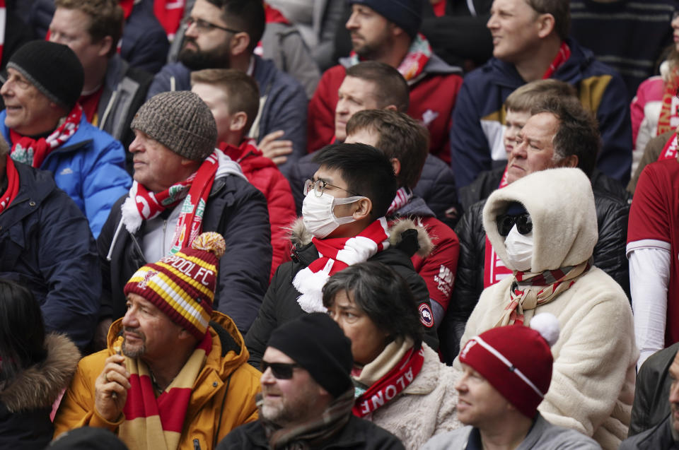 A fan wearing a protective mask attends at the English Premier League soccer match between Liverpool and Bournemouth at Anfield stadium in Liverpool, England, Saturday, March 7, 2020. (AP Photo/Jon Super)