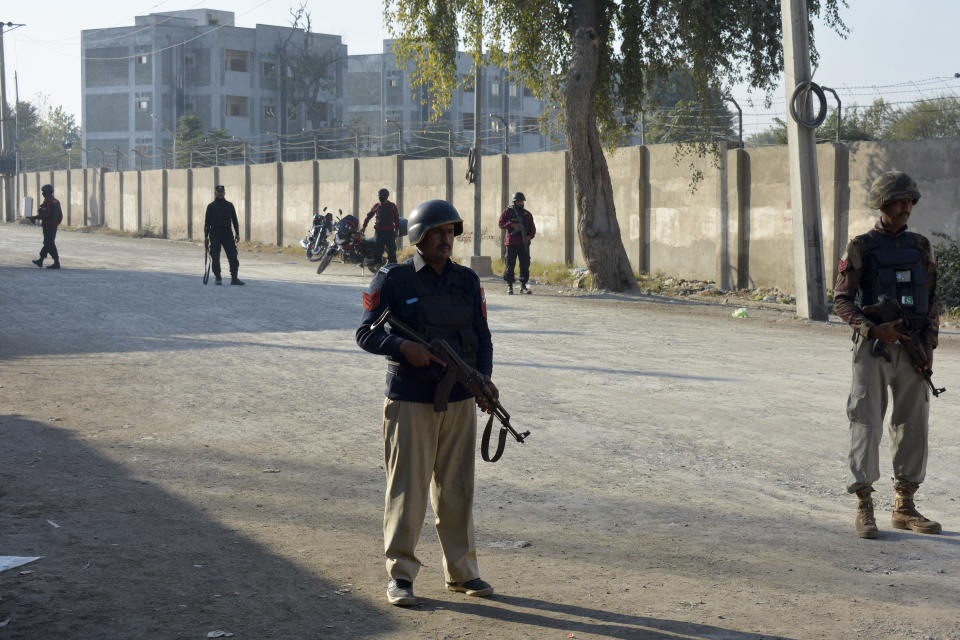 Security officials guard a blocked road leading to a counter-terrorism center after security forces starting to clear the compound seized earlier by Pakistani Taliban militants in Bannu, a northern district in the Pakistan's Khyber Pakhtunkhwa province, Tuesday, Dec. 20, 2022. Pakistan's special forces on Tuesday stormed the counter-terrorism center to free several security officials who were taken hostage earlier this week by a group of detained Pakistani Taliban militants, security officials said. (AP Photo/Muhammad Hasib)