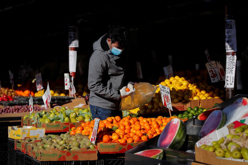 A man wears a mask and gloves as he shops at a fruit stand, during the outbreak of the coronavirus disease (COVID-19), in Brooklyn, New York