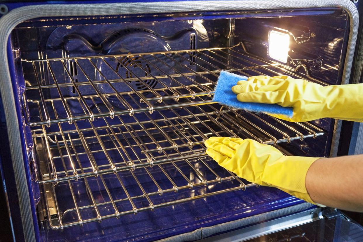 gloved hands cleaning an oven in a kitchen