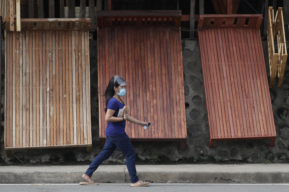 A woman wears a mask to curb the spread of the coronavirus walks past wooden beds for sale at a roadside stall on the outskirts of Manila, Philippines on Friday, Sept. 25, 2020. (AP Photo/Aaron Favila)