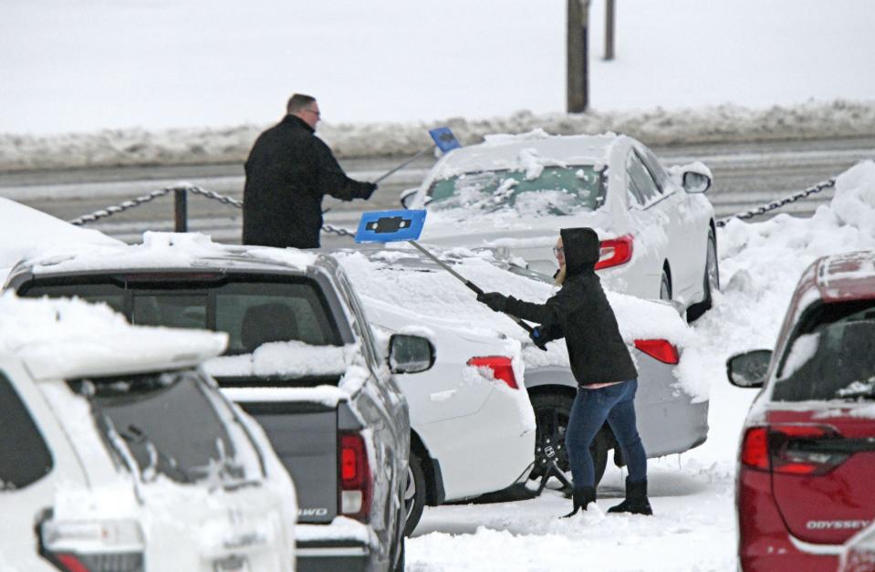 Payton Fletcher and John Lowe work to clear snow Wednesday morning from cars on the lot at Mansfield Motor Group.