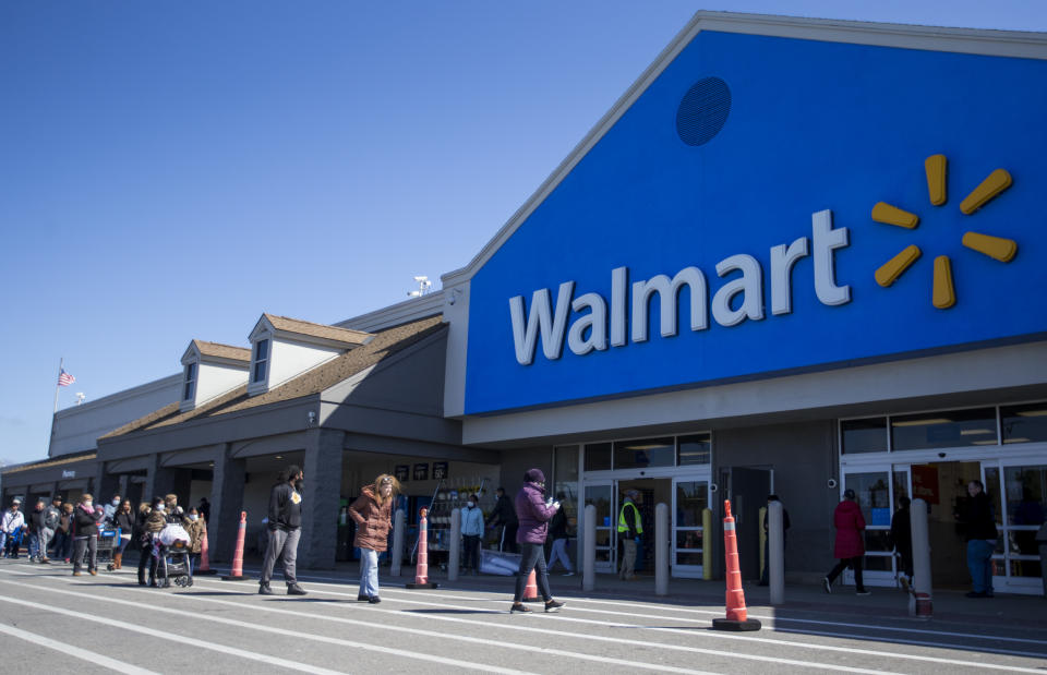 QUINCY, MA - APRIL 4: A line forms outside of the Walmart in Quincy, MA on April 4, 2020 as the store implements new restrictions on capacity during the coronavirus pandemic. People wait outside wearing masks and distanced apart. (Photo by Blake Nissen for The Boston Globe via Getty Images)