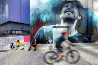 A mural painting of late soccer star Diego Maradona is seen as people pass by, during the second anniversary of his death at West Bay, in Doha, Qatar, Friday, Nov. 25, 2022. (AP Photo/Jorge Saenz)