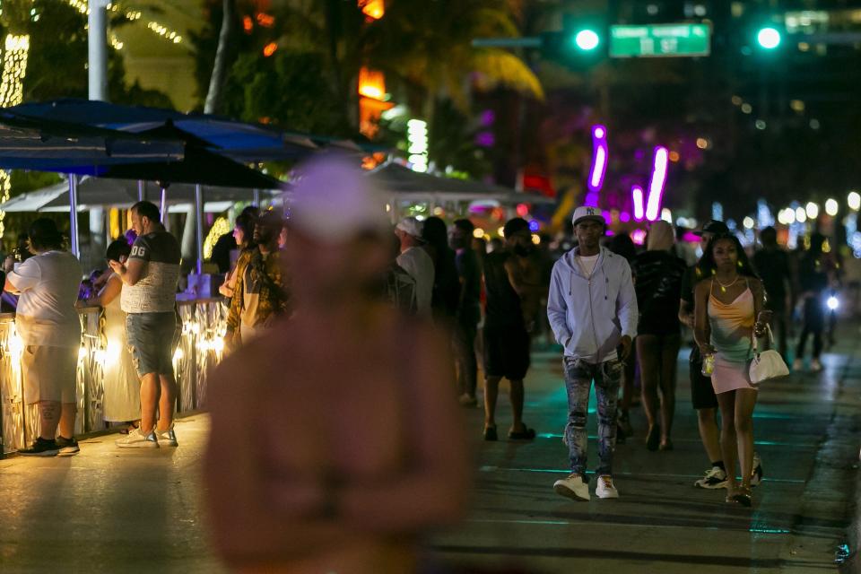 Tourists make their way down Ocean Drive during Spring Break in Miami Beach, Fla., Monday, March 22, 2021. A party-ending curfew is in effect in Miami Beach, imposed after fights, gunfire, property destruction and dangerous stampedes broke out among huge crowds of people. The curfew could extend through the end of spring break.(Matias J. Ocner/Miami Herald via AP)