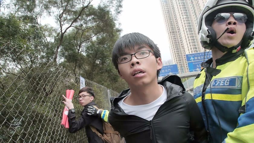 This handout photo released by Demosisto shows Hong Kong pro-democracy activist and leader of political party Demosisto, Joshua Wong, being detained by a police officer after he and others ran onto a road in Hong Kong on May 19, 2016.