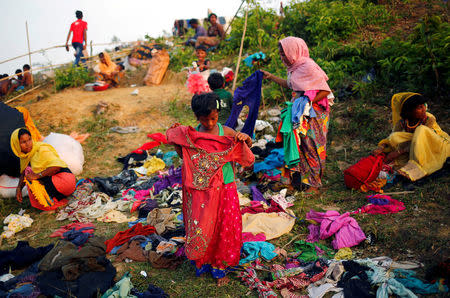 A Rohingya refugee girl checks clothes, which are donated by local people, in Cox's Bazar, Bangladesh September 16, 2017. REUTERS/Mohammad Ponir Hossain