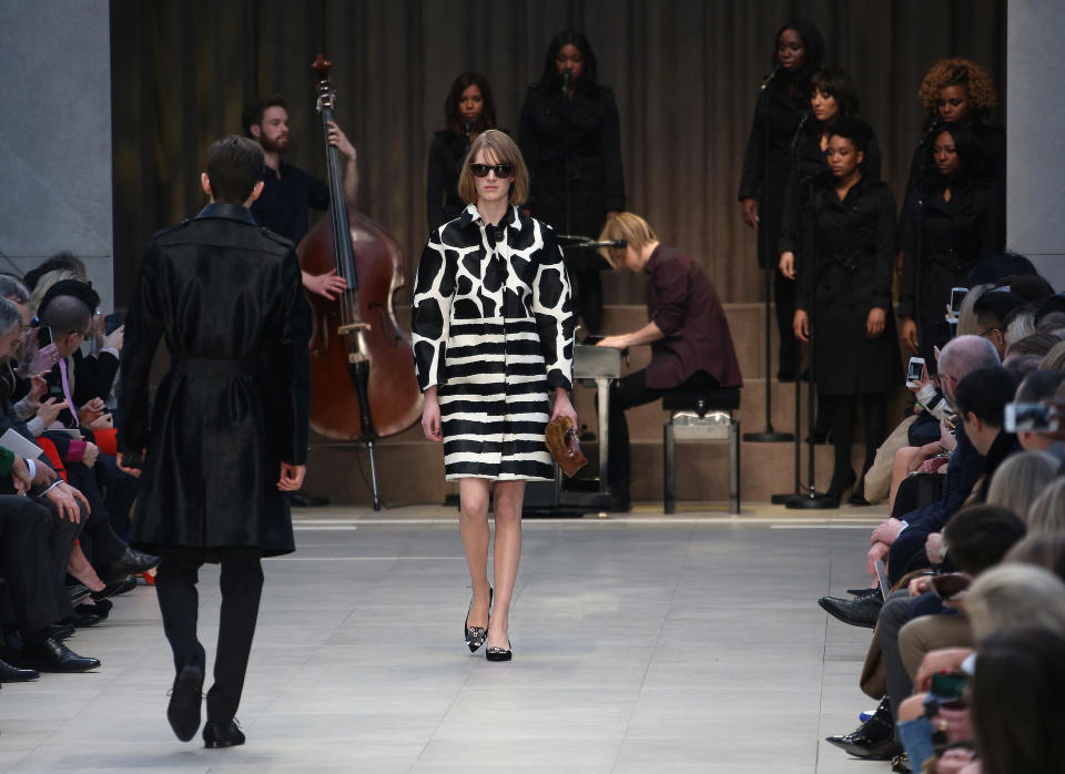 A model wears a design created by Burberry Prorsum, as British musician Tom Odell performs on the piano, during London Fashion Week, at Kensington Gardens in west London, Monday, Feb. 18, 2013. (Photo by Joel Ryan/Invision/AP)