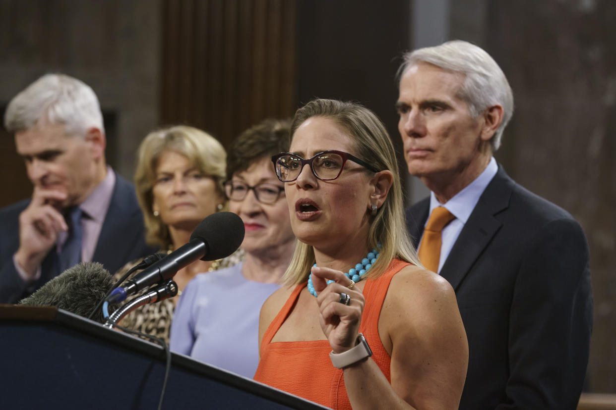 Sen. Kyrsten Sinema, D-Ariz., center, joined from left by, Sen. Bill Cassidy, R-La., Sen. Lisa Murkowski, R-Alaska, Sen. Susan Collins, R-Maine, and Sen. Rob Portman, R-Ohio, speak to reporters just after a vote to start work on a nearly $1 trillion bipartisan infrastructure package, at the Capitol in Washington, Wednesday, July 28, 2021.  (J. Scott Applewhite/AP) 
                                                                                                                                                    