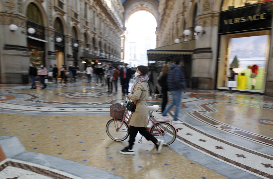 A woman wearing a sanitary mask walks in downtown Milan, Italy, Saturday, Oct. 17, 2020. Italy’s northern Lombardy region, where the European outbreak began in late February, has taken new measures to contain rebounding coronavirus infections, limiting bar service and alcohol sales, banning contact sports and closing bingo parlors. (AP Photo/Antonio Calanni)