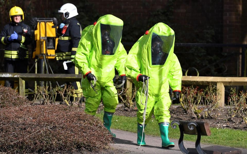 Members of the emergency services in green biohazard encapsulated suits arrive to afix the tent over the bench where Sergei and Yulia Skripal were found on March 4, 2018, in a critical condition at The Maltings shopping centre in Salisbury. Photo taken March 8, 2018. - BEN STANSALL/AFP