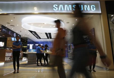 People walk in front of a Samsung smartphone showroom in Jakarta, February 24, 2015. REUTERS/Beawiharta