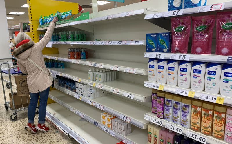 FILE PHOTO: A customer stands on tiptoes as she reaches for some hand wash in a Tesco supermarket in Manchester