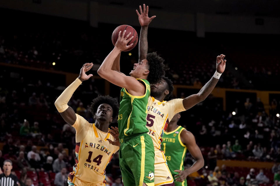 FILE - Oregon guard Will Richardson, center, shoots as Arizona State center Enoch Boakye (14) looks on during the first half of an NCAA college basketball game, Thursday, Feb. 17, 2022, in Tempe, Ariz. The Ducks return three starters, including guard Will Richardson who led the team in scoring and assists. (AP Photo/Matt York, File)