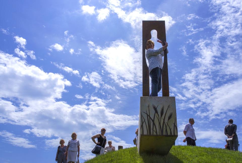 People look at the new statue of American writer Jerome David Salinger in Paminklas, Lithuania, Friday, June 19, 2020. J.D. Salinger, the American writer best known for his 1951 novel "The Catcher in the Rye," has been honored with a statue in a rye field, near the Lithuanian village where his ancestors lived. (AP Photo/Vladas Sciavinskas)