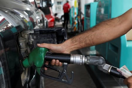 A worker fills a vehcile with petrol at a gas station in Dubai