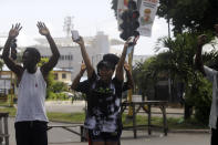 People rise their hands as they approach a police check point in Lagos, Nigeria, Thursday Oct. 22, 2020. Lagos streets were empty and shops were shuttered Thursday, as residents of Nigeria's largest city obeyed the government's curfew, stopping the protests against police brutality that had lasted for two weeks. ( AP Photo/Sunday Alamba)