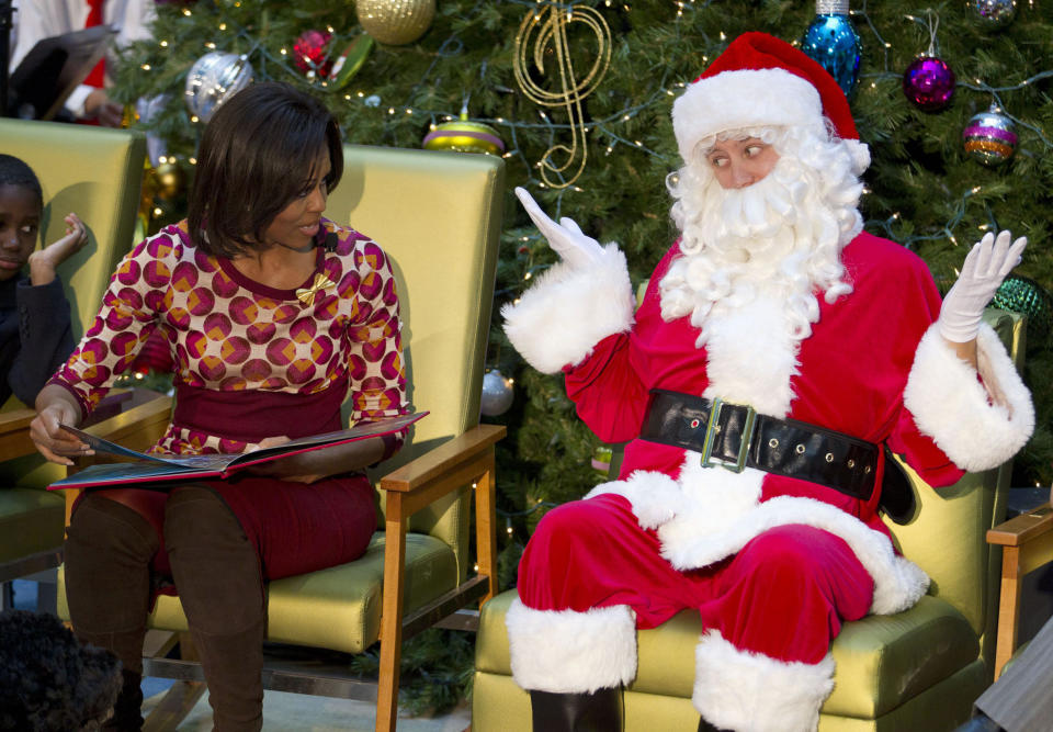 In this Dec. 12, 2011, file photo, Santa Claus gestures toward first lady Michelle Obama, at Children's National Medical Center in Washington. Why do kids believe a chubby guy in a flying sleigh can deliver joy across America? Because their parents do. A whopping 84 percent of grown-ups were once children who trusted in Santas magic, and lots cling to it still. Things are changing fast these days, with toddlers wishing for iPads, grade schoolers emailing their Christmas lists and moms wrestling over bargain toys at midnight sales. Despite all the pressures on the rituals of the season, an AP-GfK poll confirms that families are sticking by old St. Nick. (AP Photo/Evan Vucci, File)