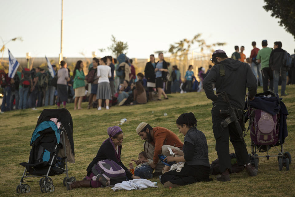 Jewish family members sit during a march from the West Bank settlement of Maaleh Adumim, to the E-1 area on the eastern outskirts of Jerusalem, Thursday, Feb. 13, 2014. Israel planned construction in the area E-1, or East 1, but froze under the international pressure in 2009. The construction in the area would effectively separate Palestinians in east Jerusalem from the West Bank. (AP Photo/Sebastian Scheiner)