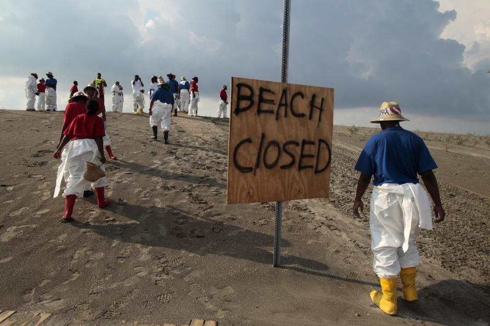 FILE - Workers head to the beach to clean up oil residue in Grand Isle, La., May 30, 2010. When a deadly explosion destroyed BP's Deepwater Horizon drilling rig in the Gulf of Mexico, tens of thousands of ordinary people were hired to help clean up the environmental devastation. (AP Photo/Jae C. Hong, File)