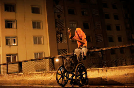 A "pichador", a graffiti artist who tags building, who lost his legs after suffering an accident while hopping trains, poses for a photograph on a street after tagging a wall with his personal signature, called "pichacao", in Sao Paulo, Brazil, April 19, 2017. REUTERS/Nacho Doce