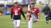 Minnesota Vikings quarterbacks Jake Browning, right, and Danny Etling take part in stretching during an NFL football training camp at TCO Stadium, Tuesday, Aug. 3, 2021, in Eagan, Minn. (AP Photo/Jim Mone)