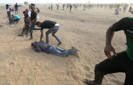 Palestinians react to tear gas fired by Israeli troops during a protest calling for lifting the Israeli blockade on Gaza and demanding the right to return to their homeland, at the Israel-Gaza border fence in the southern Gaza Strip October 5, 2018. REUTERS/Ibraheem Abu Mustafa