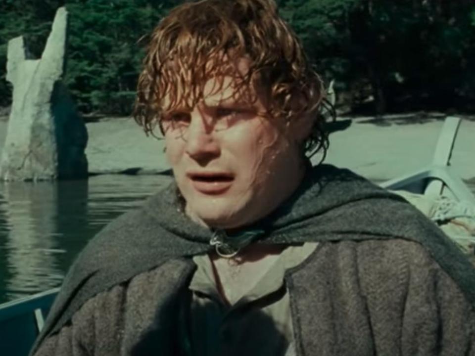 samwise wearing a gray cape in a boat in lord of the rings