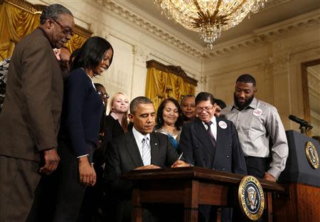 U.S. President Barack Obama signs an executive order increasing the minimum wage for employees of federal contractors, in the East Room at the White House in Washington February 12, 2014. Obama signed the executive order on Wednesday to raise the minimum wage for federal contract workers to $10.10 an hour starting next year and encouraged employers nationwide to increase wages for their workers. The order will affect workers starting on Jan. 1, 2015, and applies to new contracts and replacements for expiring contracts. REUTERS/Larry Downing