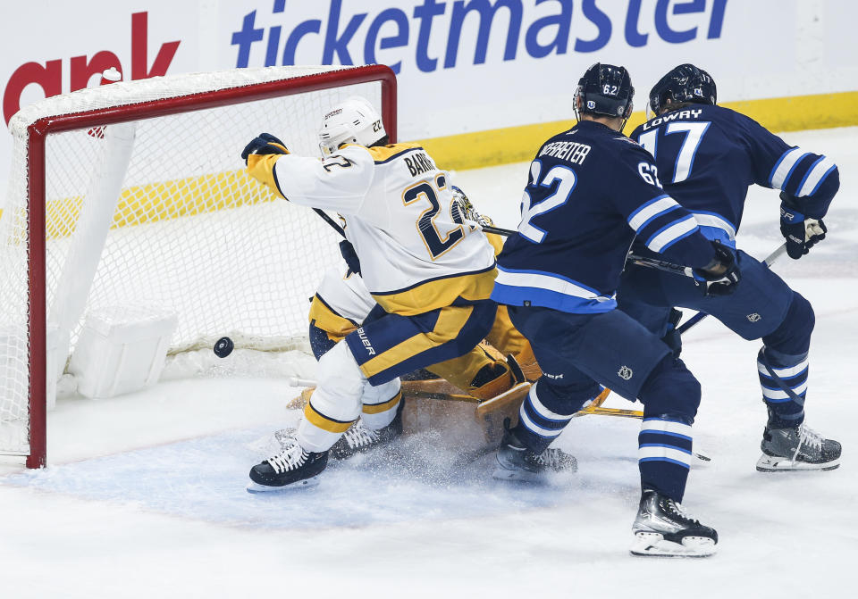 Winnipeg Jets' Nino Niederreiter (62) and Adam Lowry (17) attack the net as Jets' Mason Appleton's (not shown) shot goes off the skate of Nashville Predators' Tyson Barrie (22) and into the net during first-period NHL hockey game action in Winnipeg, Manitoba, Thursday, Nov. 9, 2023. (John Woods/The Canadian Press via AP)