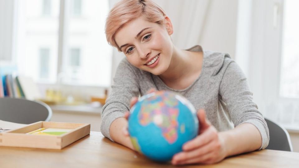 Una mujer sostiene un globo terráqueo.