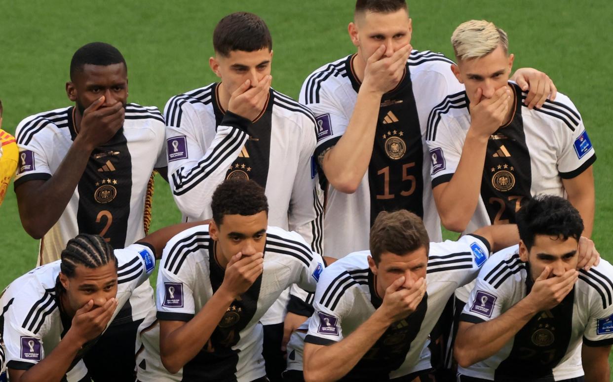 Germany players cover their mouths as they pose for a team photo before Japan match - Getty Images