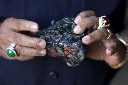 A buyer checks a jade stone near a mine dump at a Hpakant jade mine in Kachin state, Myanmar November 29, 2015. REUTERS/Soe Zeya Tun