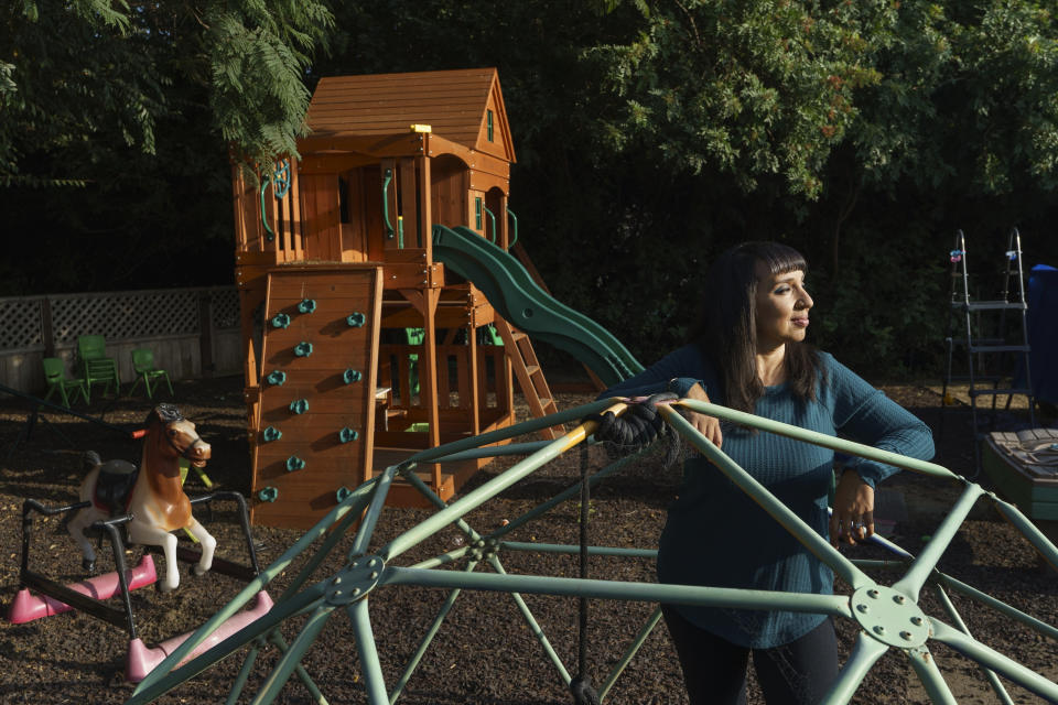 Mary De La Rosa stands inside a play structure in her home backyard, that once housed the now-closed child care program, Creative Explorers, Wednesday, Oct. 21, 2020, in Los Angeles. When De La Rosa closed her toddler and preschool program in March because of the coronavirus pandemic, she fully expected to serve the children again some day. In the end, though, Creative Explorers closed for good. The story of De La Rosa’s program is being repeated across the country as the pandemic’s effects ripple through child care, disproportionately affecting Black and Latino-owned centers in an industry that has long relied on providers of color. (AP Photo/Damian Dovarganes)