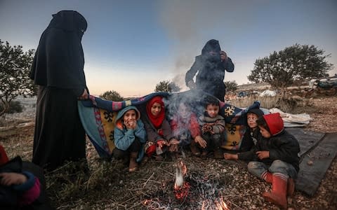 Syrian families, who have been forced to displace despite attacks carried out by Assad regime and Russia, sit on soil field despite the cold weather during winter season at Harbanush village in Idlib, Syria - Credit: Anadolu Agency&nbsp;