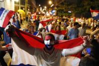 A youth holds a national Paraguay national flag as he marches with others in protest against the project to change the country's constitution, in Asuncion, Paraguay, Thursday, March 30, 2017. The country's upper house of Congress is split over a proposal to amend the constitution and allow for the re-election of former presidents. (AP Photo/Jorge Saenz)