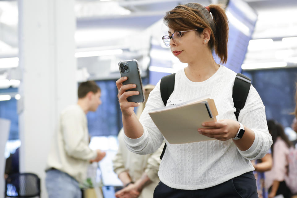 Mahtad Parsamehr, of Atlanta, checks her phone while handing out resumes during the Startup Student Connection job fair, Wednesday, March 29, 2023, in Atlanta. For the thousands of workers who'd never experienced upheaval in the tech sector, the recent mass layoffs at companies like Google, Microsoft, Amazon and Meta came as a shock. Now they are being courted by long-established employers whose names aren't typically synonymous with tech work, including hotel chains, retailers, investment firms, railroad companies and even the Internal Revenue Service. (AP Photo/Alex Slitz)