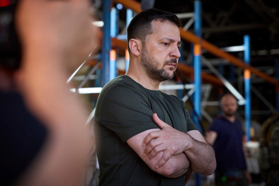 A side of Ukraine's President Volodymyr Zelenskyy wearing a green t-shirt and with his armed folded with a worried expression on his face