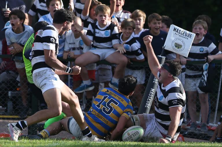 Leonardo Mazzini anota el tercer try de CASI y lo festeja con Jerónimo Solveyra, la figura de la goleada a Hindú, ante la impotencia de Lisandro Rodríguez; triunfado de la Academia en la tercera fecha del Top 12 de URBA.