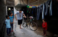 Palestinian cyclist Alaa Al-Daly, 21, who lost his leg by a bullet fired by Israeli troops, talks with his sister while holding his bicycle at his house in Rafah, southern Gaza Strip, April 18, 2018. REUTERS/Suhaib Salem