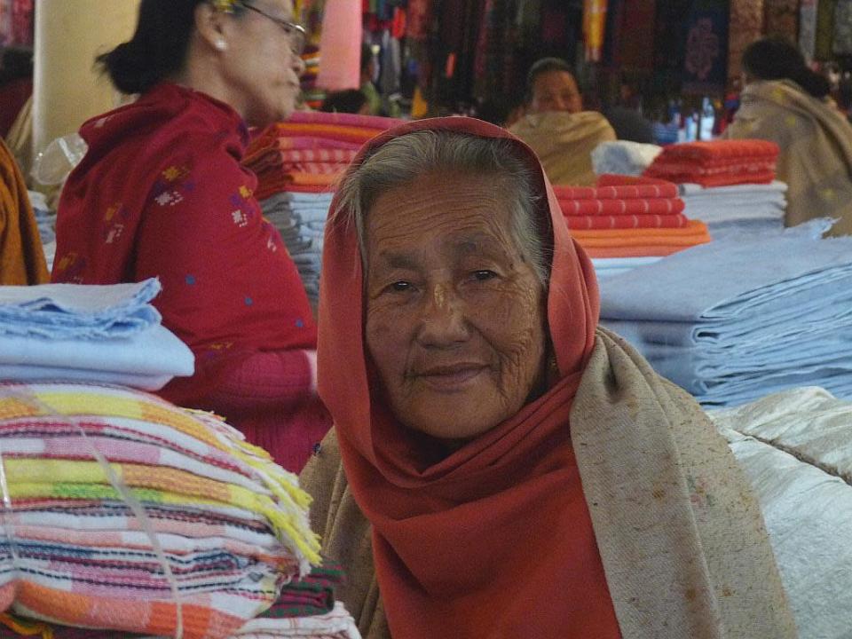 This elderly Ima has been selling phaneks and shawls for many years at the Ima Market, long before it moved to these spacious galleries of concrete.