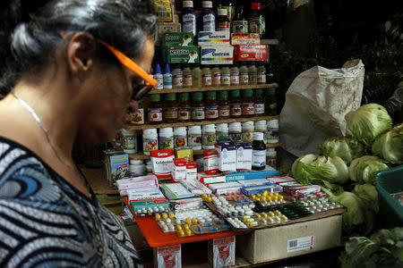 A woman walks past a fruit and vegetables stall selling medicines at a market in Rubio, Venezuela December 5, 2017. REUTERS/Carlos Eduardo Ramirez