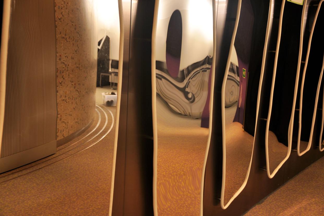 Wall of five distorted mirrors browns and dark oranges, dark orange floor on the right