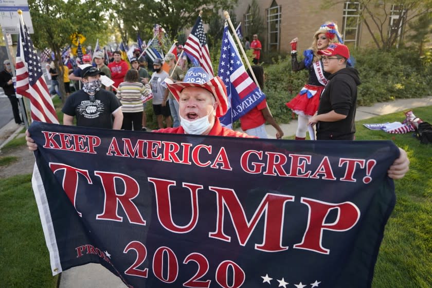 A supporter of President Donald Trump holds a banner before the vice presidential debate between Vice President Mike Pence and Sen. Kamala Harris, at the University of Utah on Wednesday, Oct. 7, 2020, in Salt Lake City. (AP Photo/Rick Bowmer)