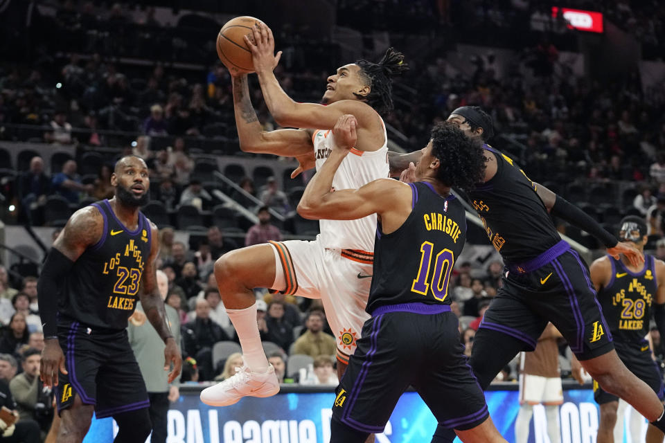 San Antonio Spurs guard Devin Vassell, center, drives to the basket past Los Angeles Lakers guard Max Christie (10) during the first half of an NBA basketball game in San Antonio, Friday, Dec. 15, 2023. (AP Photo/Eric Gay)