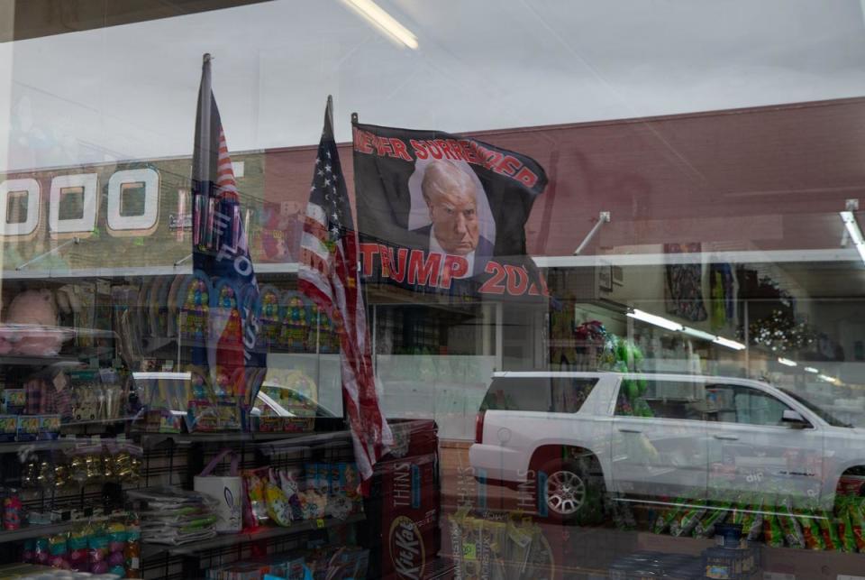 A "never surrender" flag bearing former President Donald Trump's mugshot flies in the reflection of a shop window in downtown Eagle Pass ahead of his visit to Shelby Park on Feb. 29, 2024.