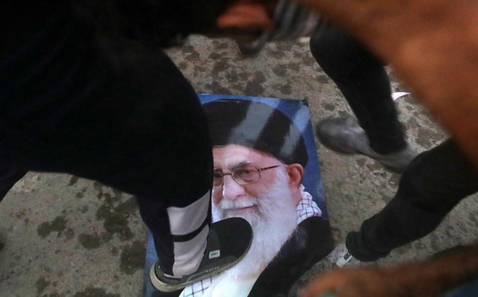 Protesters trample a portrait of Iran's supreme Leader Ayatollah Ali Khamenei, during the storming and burning the Iranian consulate in Basra, 340 miles (550 km) southeast of Baghdad, Iraq, Friday, Sept. 7, 2018. Hundreds of angry protesters in Basra took to the streets on Thursday night. Some clashed with security forces, lobbing Molotov cocktails and setting fire to a government building as well as the offices of Shiite militias. At least three people were shot dead in confrontations with security forces. (AP Photo/Nabil al-Jurani)