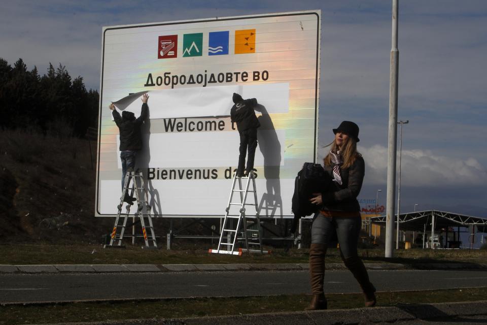 Workers replace signage with an adhesive banner in the southern border with Greece, near Gevgelija, North Macedonia, Wednesday, Feb. 13, 2019. Workers in the newly renamed North Macedonia have begun replacing road signs to reflect the change in their country's name, following a deal with neighboring Greece to end a nearly three decade-long dispute and secure NATO membership. (AP Photo/Boris Grdanoski)