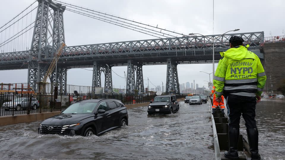 A police officer from the NYPD Highway Patrol oversees a flooded street on Friday. - Andrew Kelly/Reuters